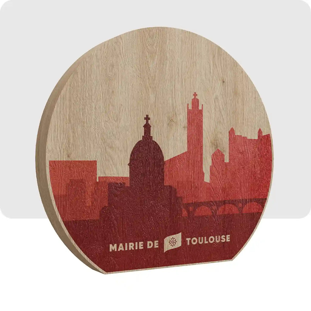 Trophée en bois de forme ronde avec une impression de couleur rouge foncé et clair représentant la ville de Toulouse.